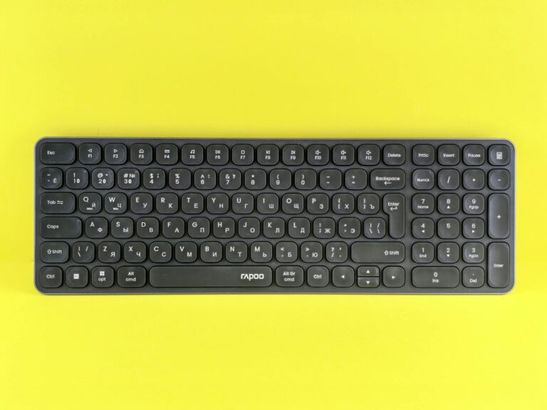 Black wireless keyboard with Cyrillic markings on a bright yellow background.