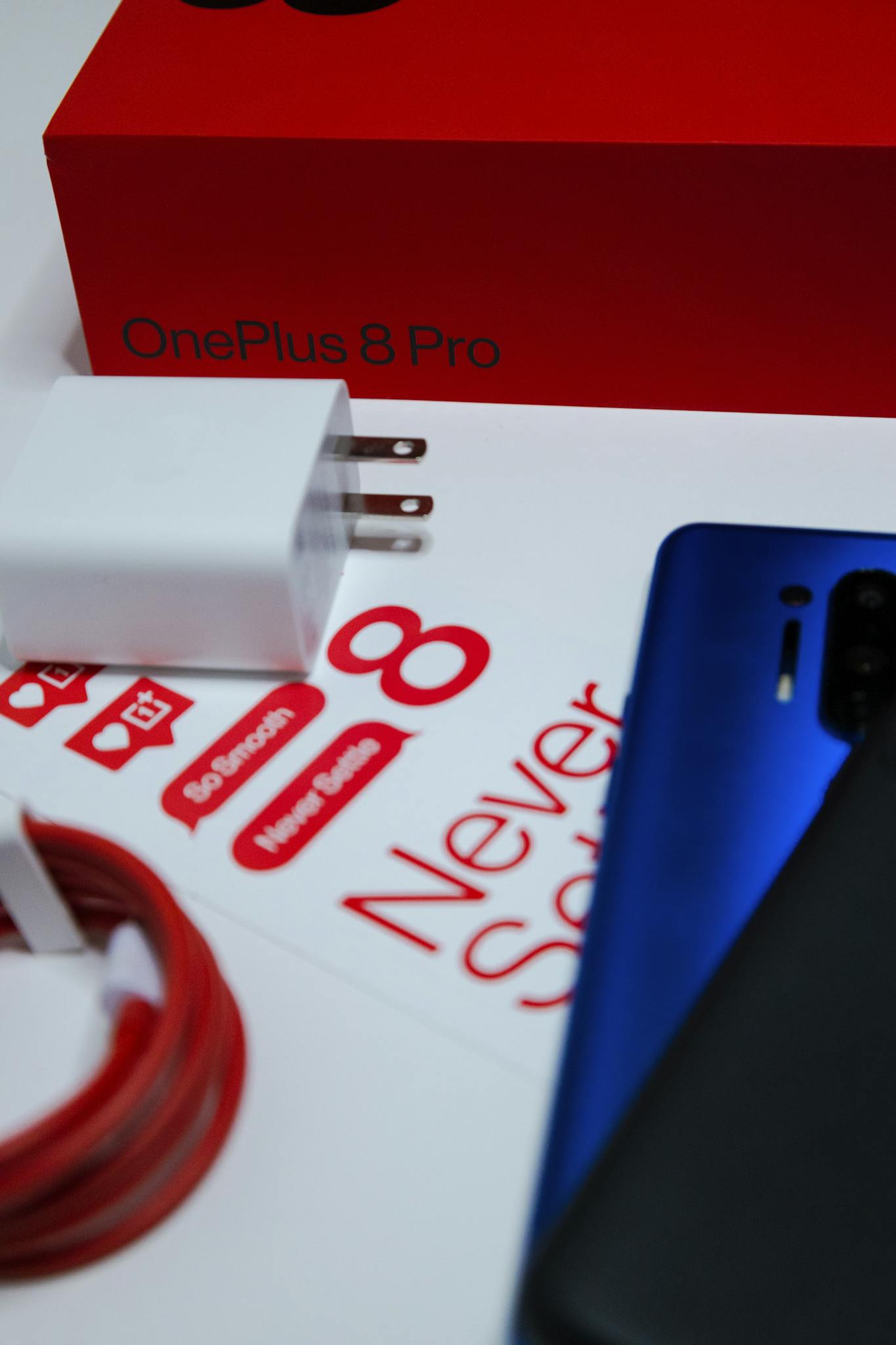 Close-up of OnePlus 8 Pro phone, charger, and packaging for an unboxing experience.