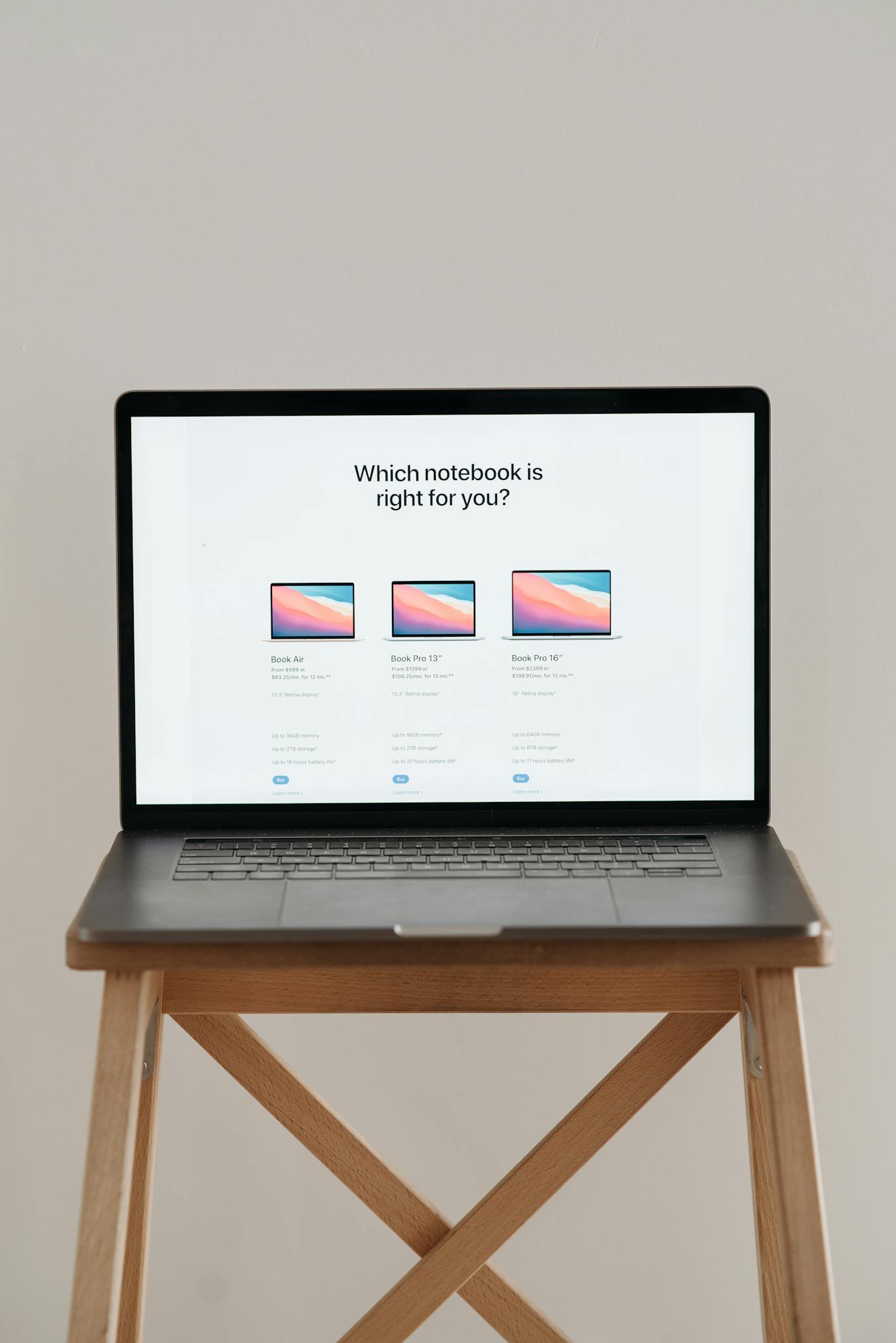 Laptop on a wooden stand with screen showing notebook comparison.