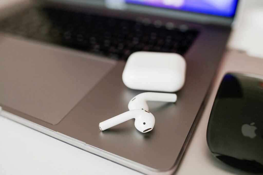 White wireless earbuds and charging case on a sleek laptop close-up.